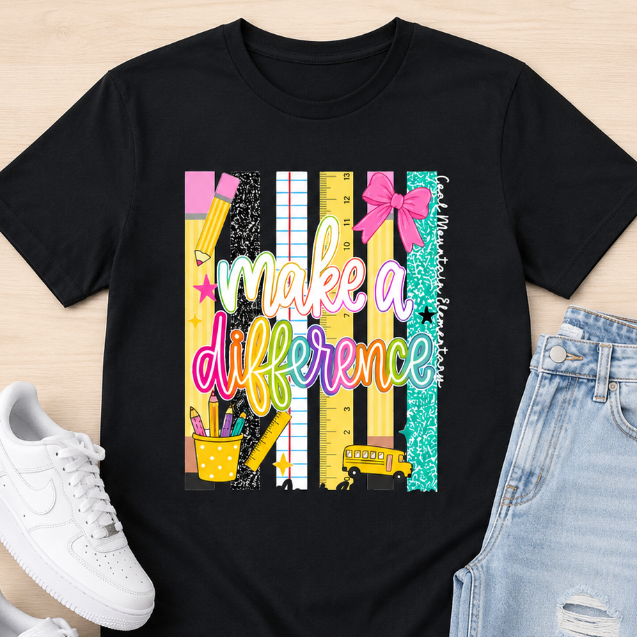 A black graphic t-shirt featuring a colorful school-themed design with the phrase 'make a difference' in pastel script over striped and patterned vertical bars. The shirt is styled in a flat lay on a light wood background, accompanied by white sneakers and light-wash distressed jeans.