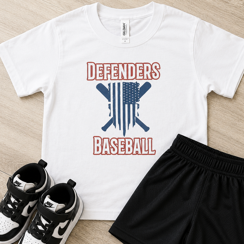 A kids' athletic outfit set featuring a white short-sleeve t-shirt with a red and blue 'Defenders Baseball' graphic, black athletic shorts with a white Nike swoosh, and black-and-white Nike sneakers, arranged on a light wood floor.