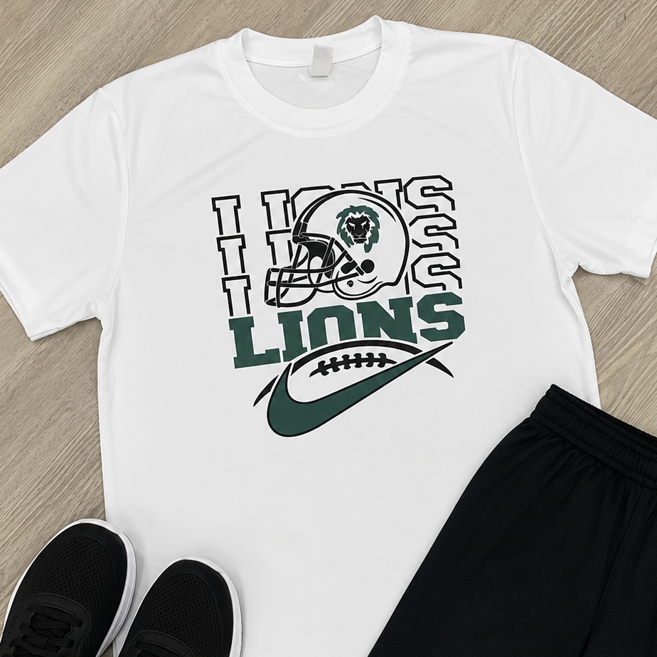 A flat-lay outfit set featuring a white short-sleeve graphic T-shirt with a green and black football helmet and 'LIONS' design, black athletic shorts with a white Under Armour logo, and a pair of black sneakers, arranged on a light wood floor.