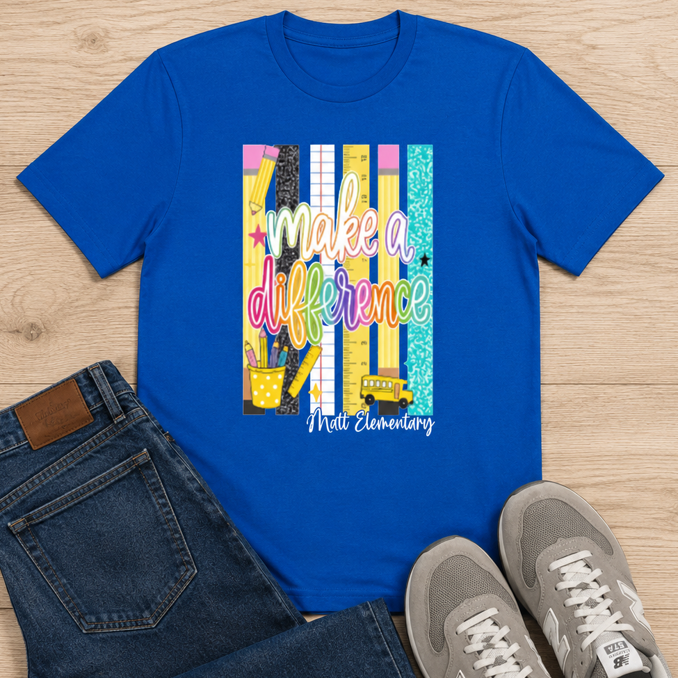 A flat-lay outfit arrangement featuring a bright blue graphic T-shirt with the text 'make a difference' and 'Mile Elementary' on a wood floor, styled with dark blue jeans and gray sneakers.
