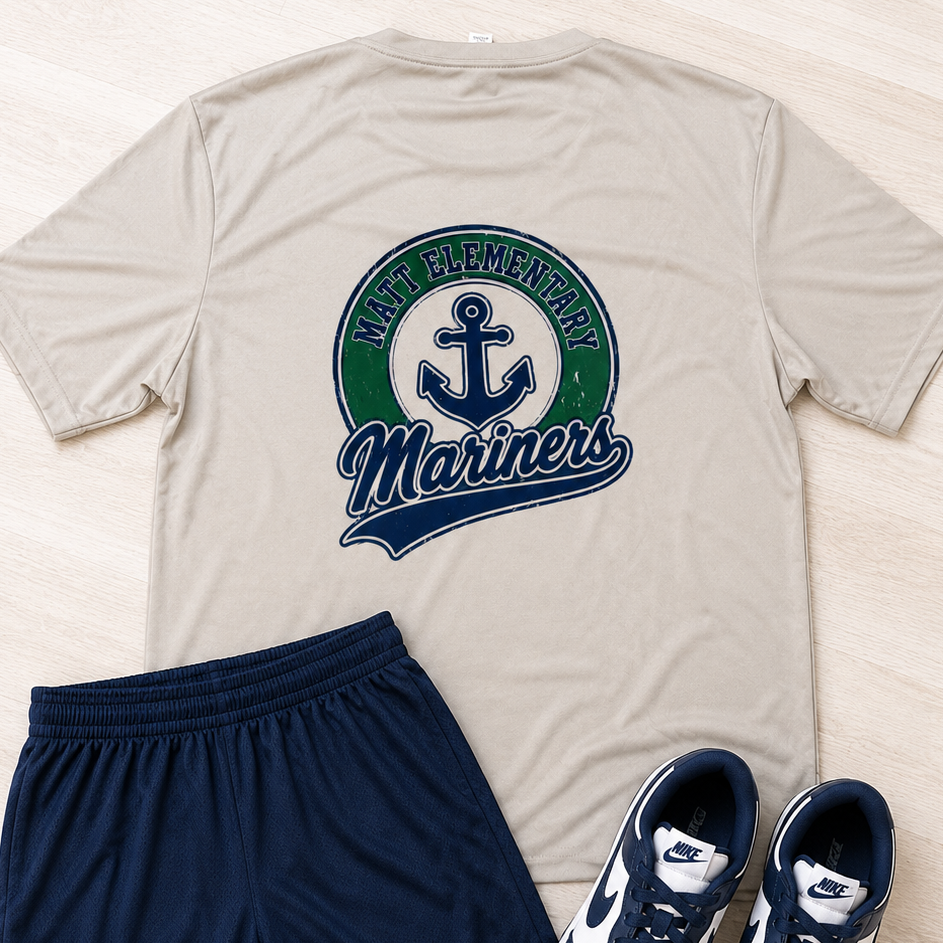 A flat-lay outfit consisting of a beige t-shirt with a green and navy Seattle Mariners logo, navy blue athletic shorts, and a pair of white and navy Nike sneakers on a light wood background.