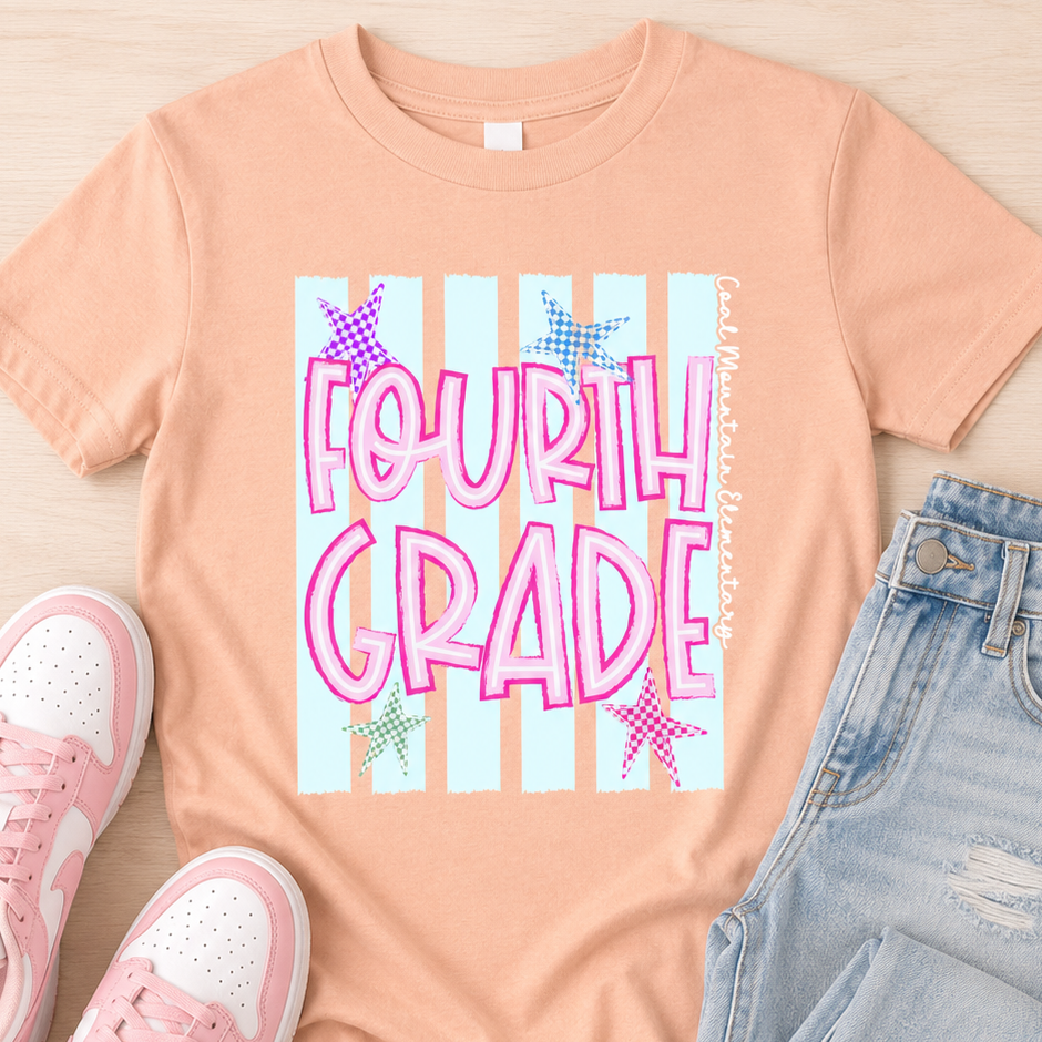 A peach-colored graphic t-shirt featuring 'FOURTH GRADE' in pink letters over light blue and white stripes with pink stars. The t-shirt is styled in a flat lay on a light wood background, accompanied by pink sneakers and light-wash jeans.