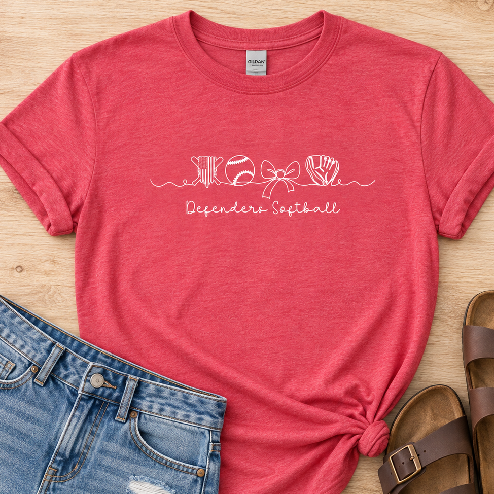 A heather coral pink t-shirt with a white graphic reading 'KHOE Defender's Softball' styled in a flat lay on a light wood background, paired with distressed denim shorts and brown slide sandals.