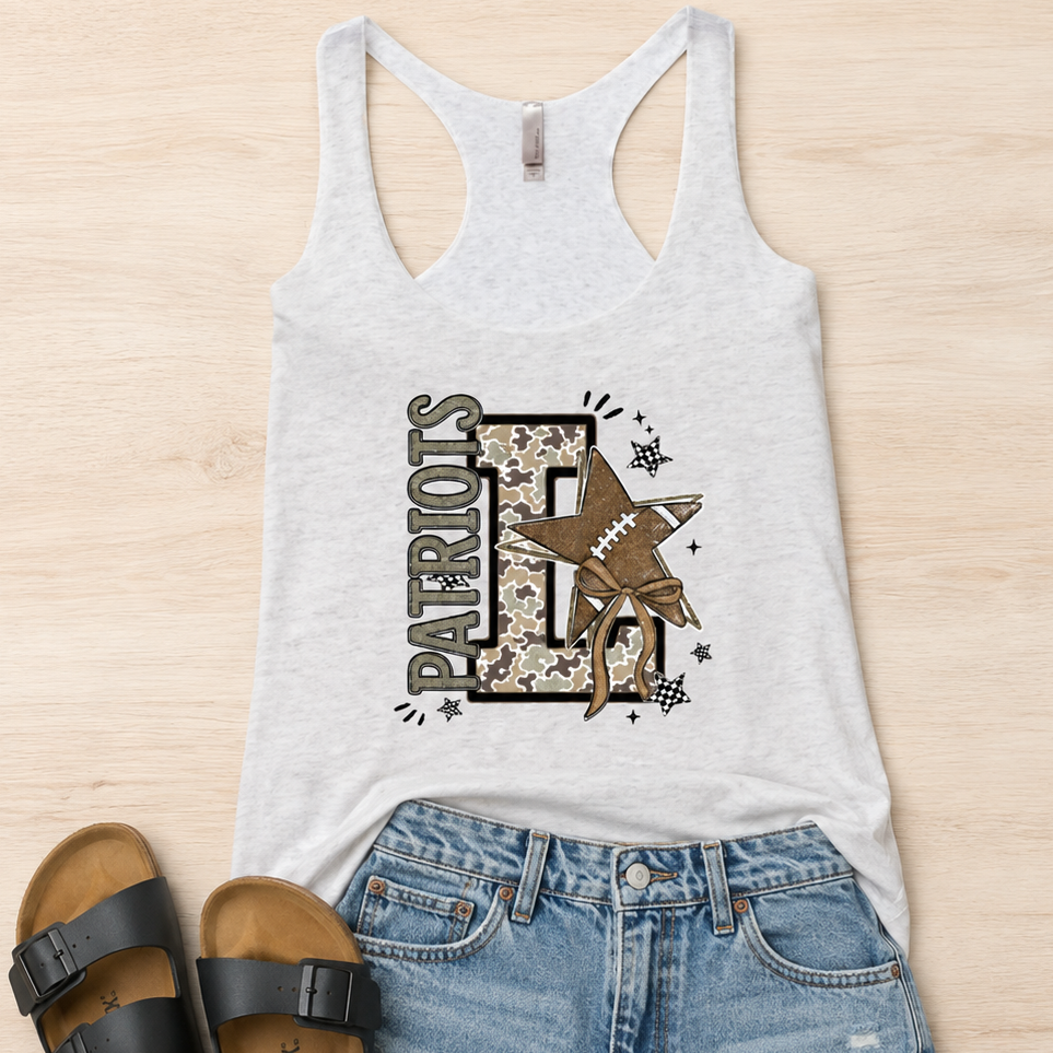 A flat-lay outfit arrangement featuring a light gray racerback tank top with a 'Patriots FF' graphic, paired with denim shorts and black slide sandals on a light wood background.