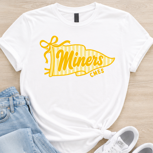 A styled flat-lay of a white short-sleeve T-shirt with a yellow pennant graphic reading 'Miners CMEs,' paired with light blue jeans and white sneakers on a light wood background.