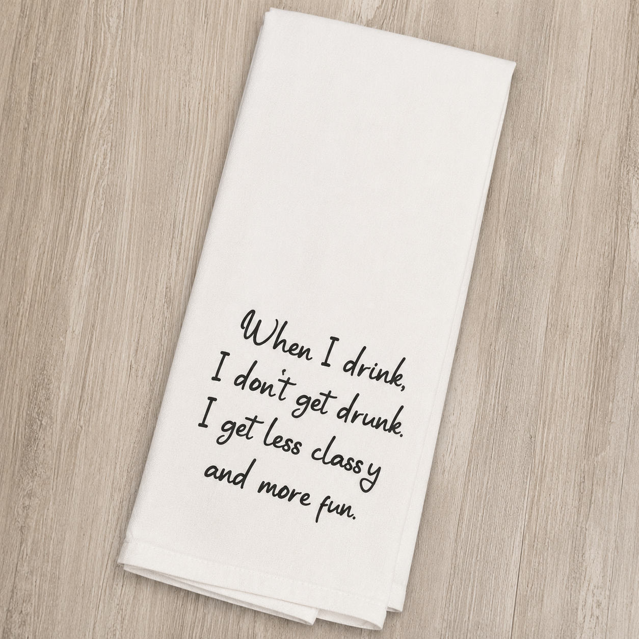 A white kitchen towel with black cursive text that reads 'When I drink, I don't get drunk. I get less classy and more fun.