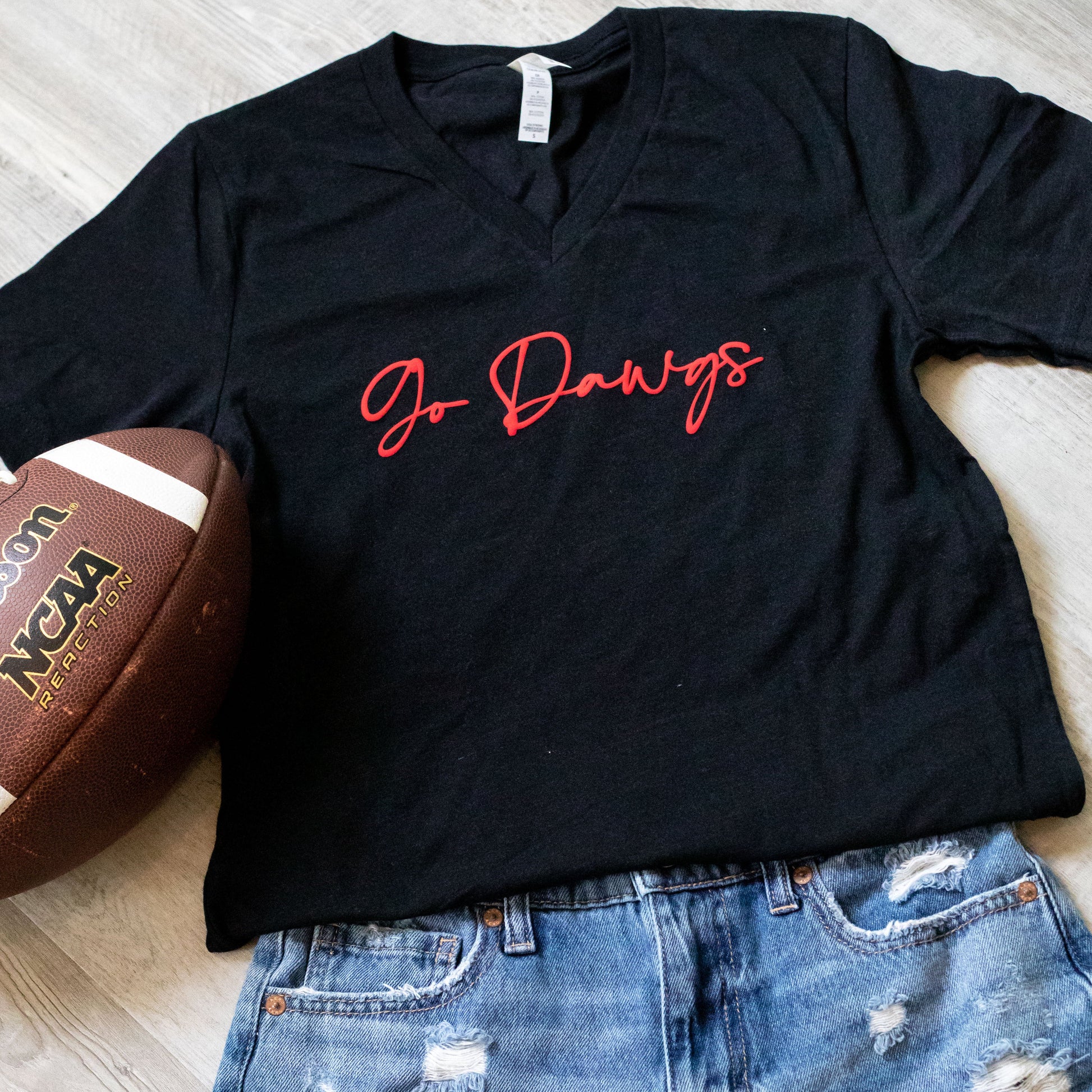 A black puffy vinyl shirt with 'GO DAWGS' text in red and white, displayed next to a brown football with the 'Georgia' and 'Athens' logos.