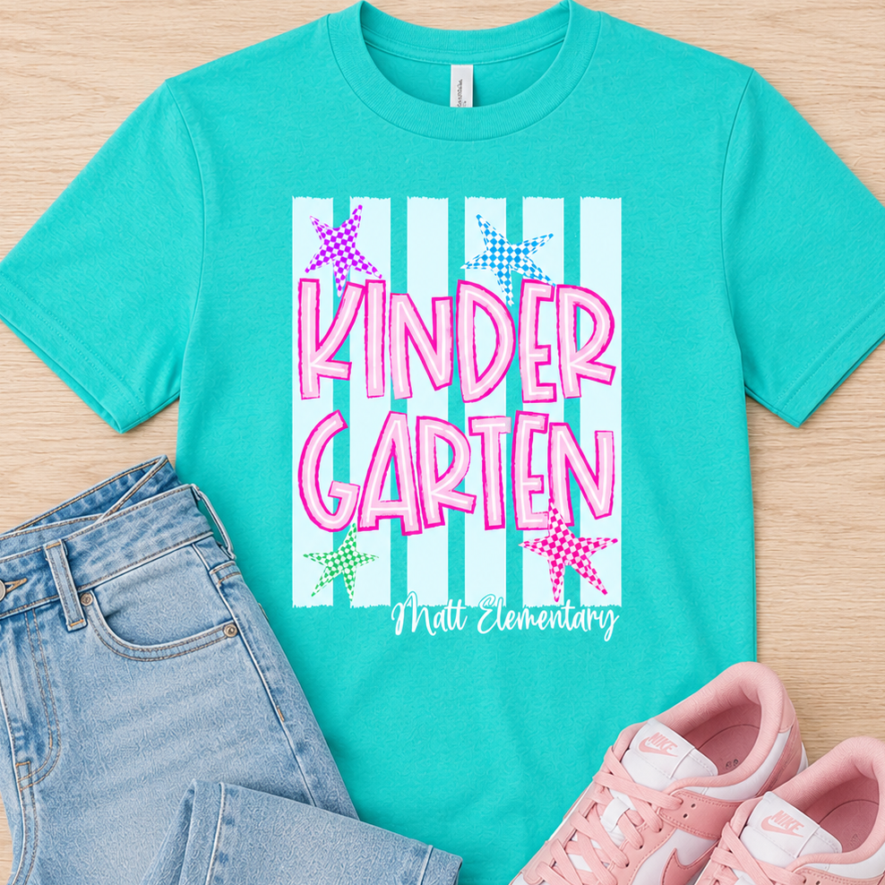 A styled flat-lay featuring a turquoise short-sleeve graphic T-shirt with 'KINDER GARTEN' and 'Mall Elementary' printed on the front, paired with light blue jeans and pink sneakers on a light wood background.