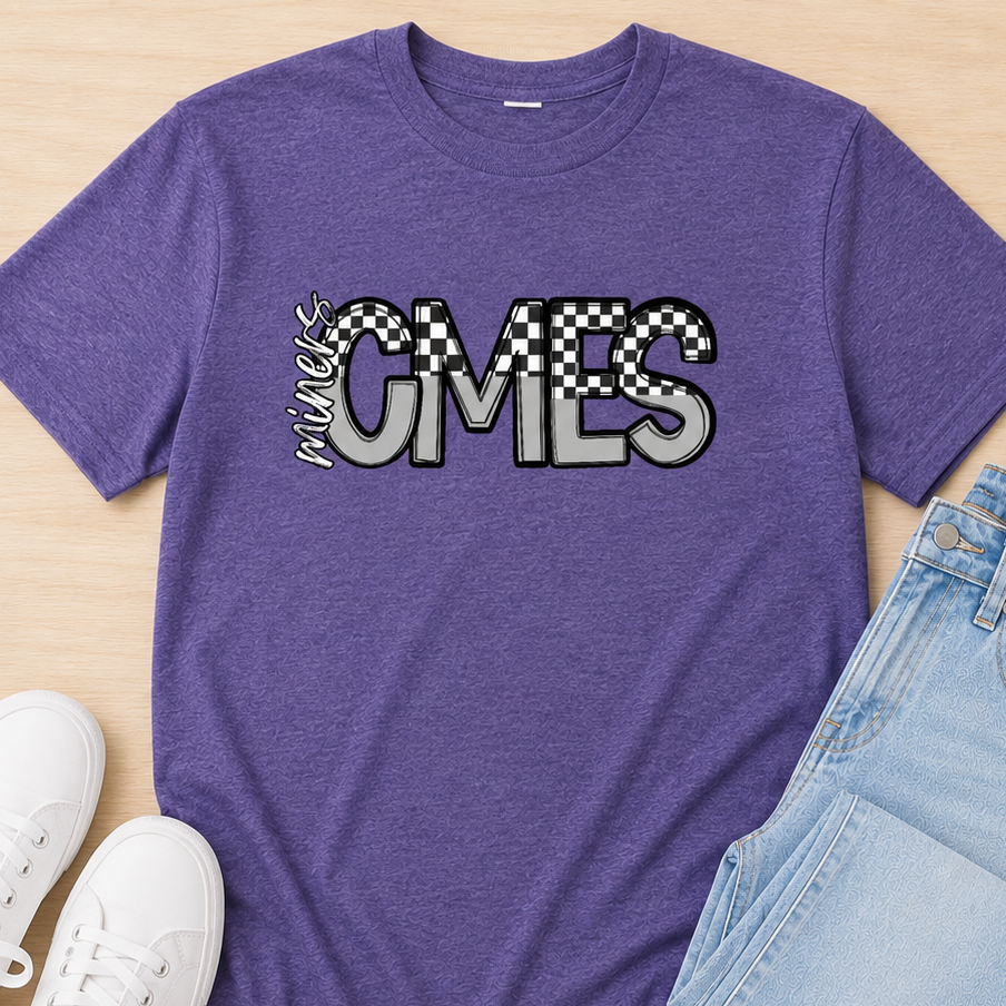 A heather purple graphic t-shirt with 'My CMES' printed across the chest, styled in a flat lay with light blue jeans and white sneakers on a light wood background.