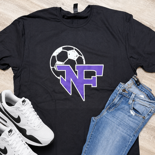 A black graphic t-shirt with a purple and white 'NF' logo over a soccer ball, styled in a flat lay with blue jeans and white Nike sneakers on a light wood floor.