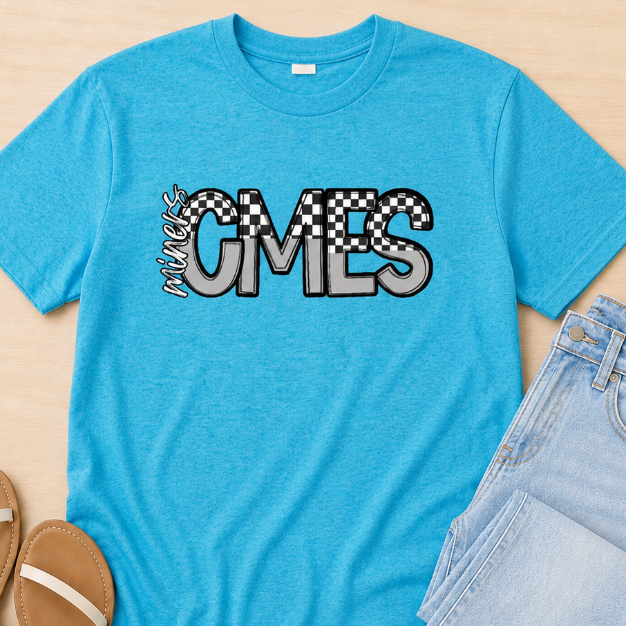 A bright blue heather t-shirt with a 'Music Comes' graphic in black and white, styled in a flat lay with light blue jeans and tan sandals on a light wood background.